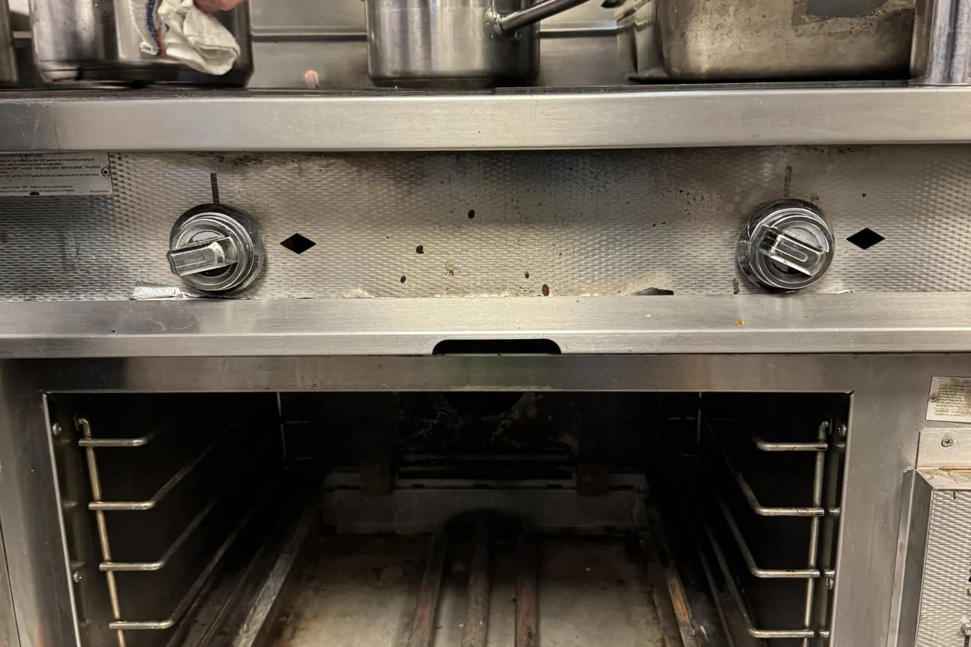 Commercial cooking equipment repair technician servicing a fryer on a restaurant hot line