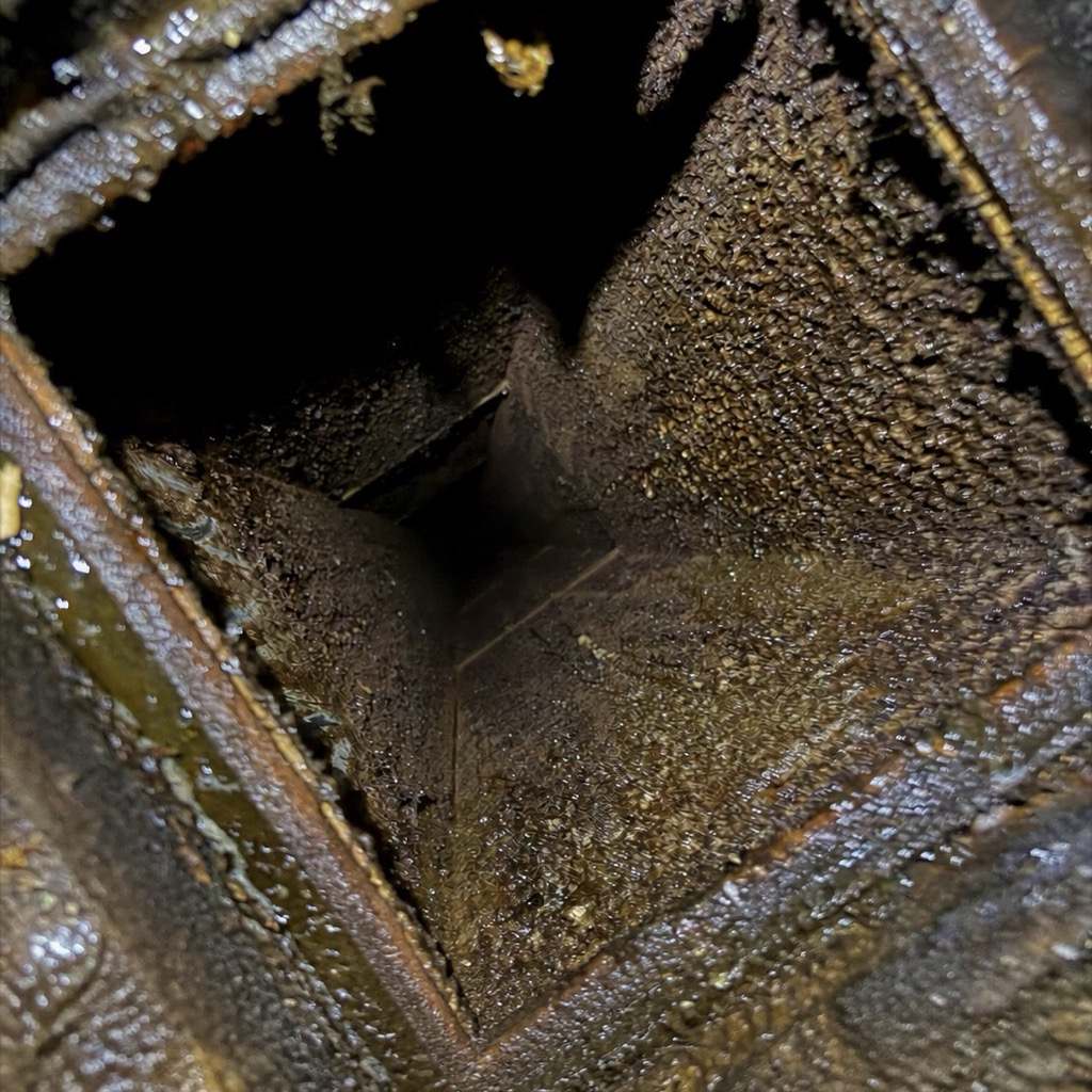 Commercial kitchen exhaust duct interior thick with grease before cleaning