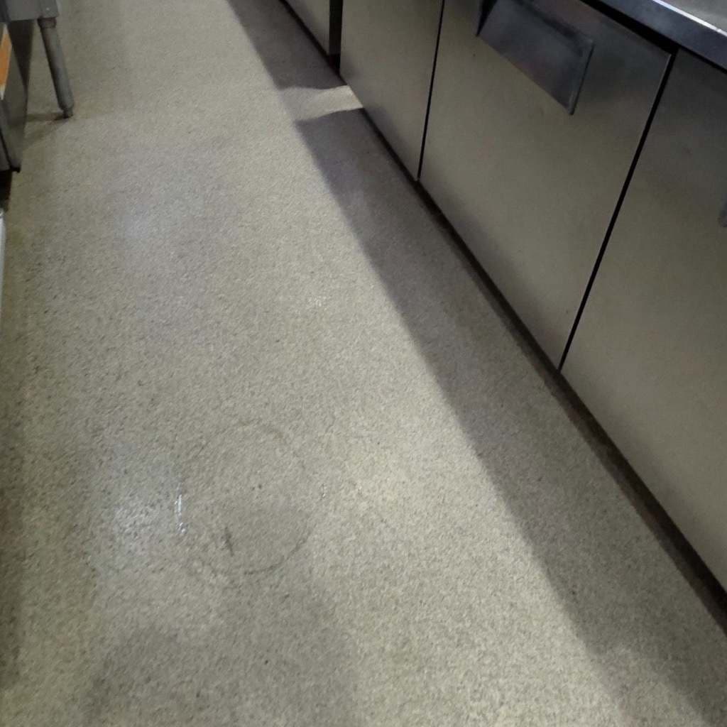 The same kitchen aisle floor scrubbed back to clean concrete