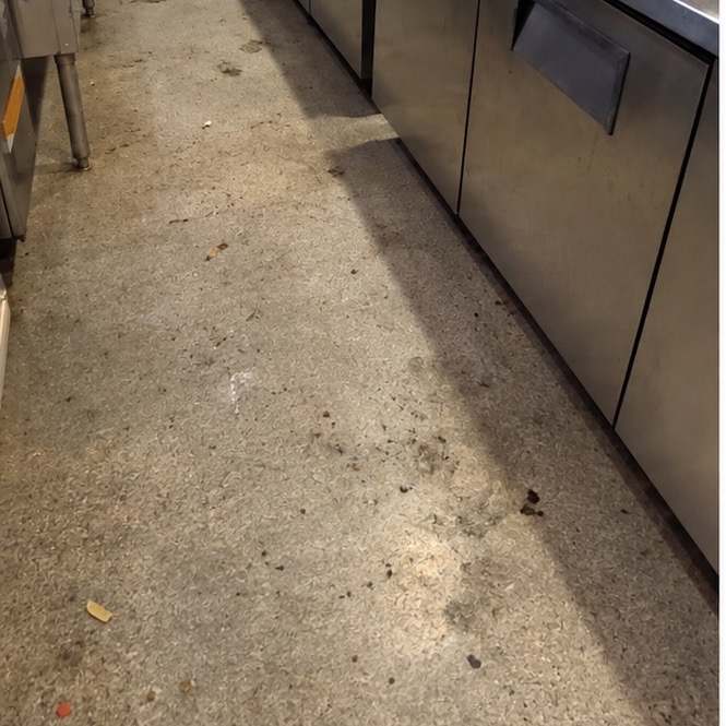 Kitchen aisle floor grimed with grease and debris before cleaning