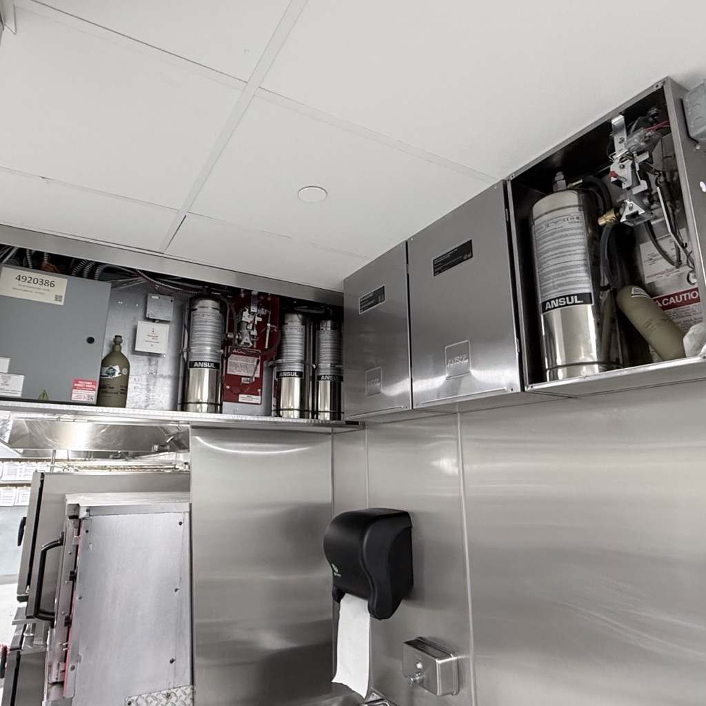 Kitchen fire suppression cabinets opened for inspection, cylinders visible