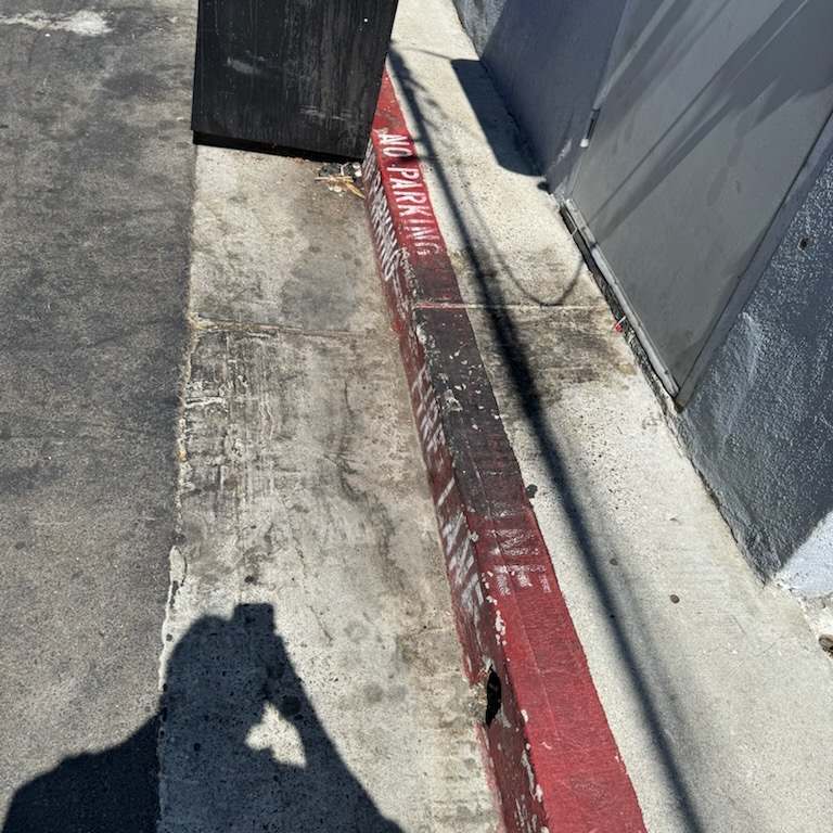 Painted red curb stained with grease and grime before pressure washing