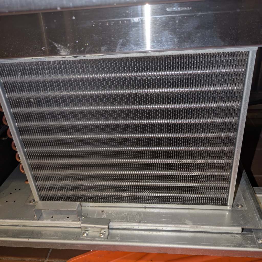 The same condenser coil cleaned back to bare aluminium fins