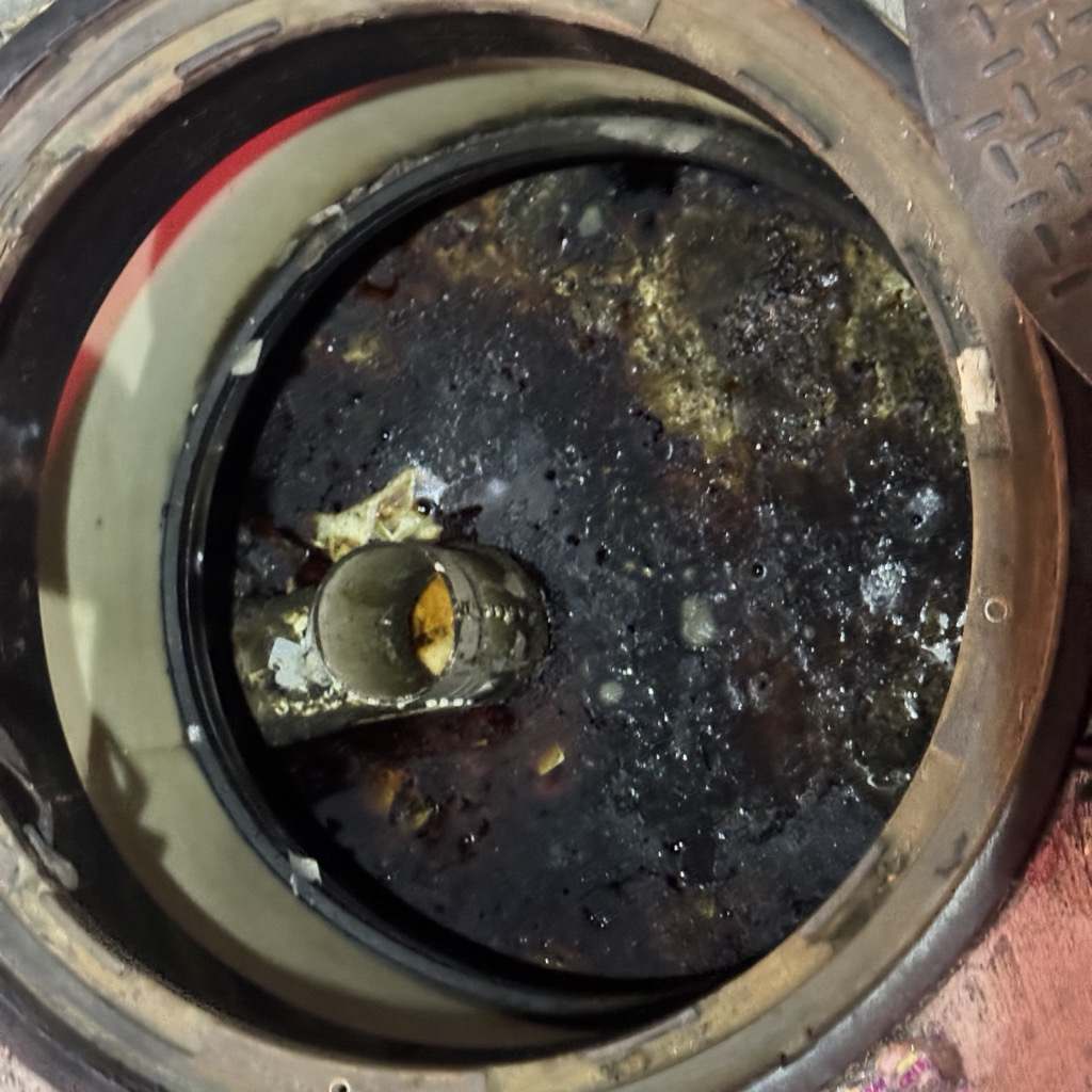 Grease trap filled with accumulated fats, oils and grease